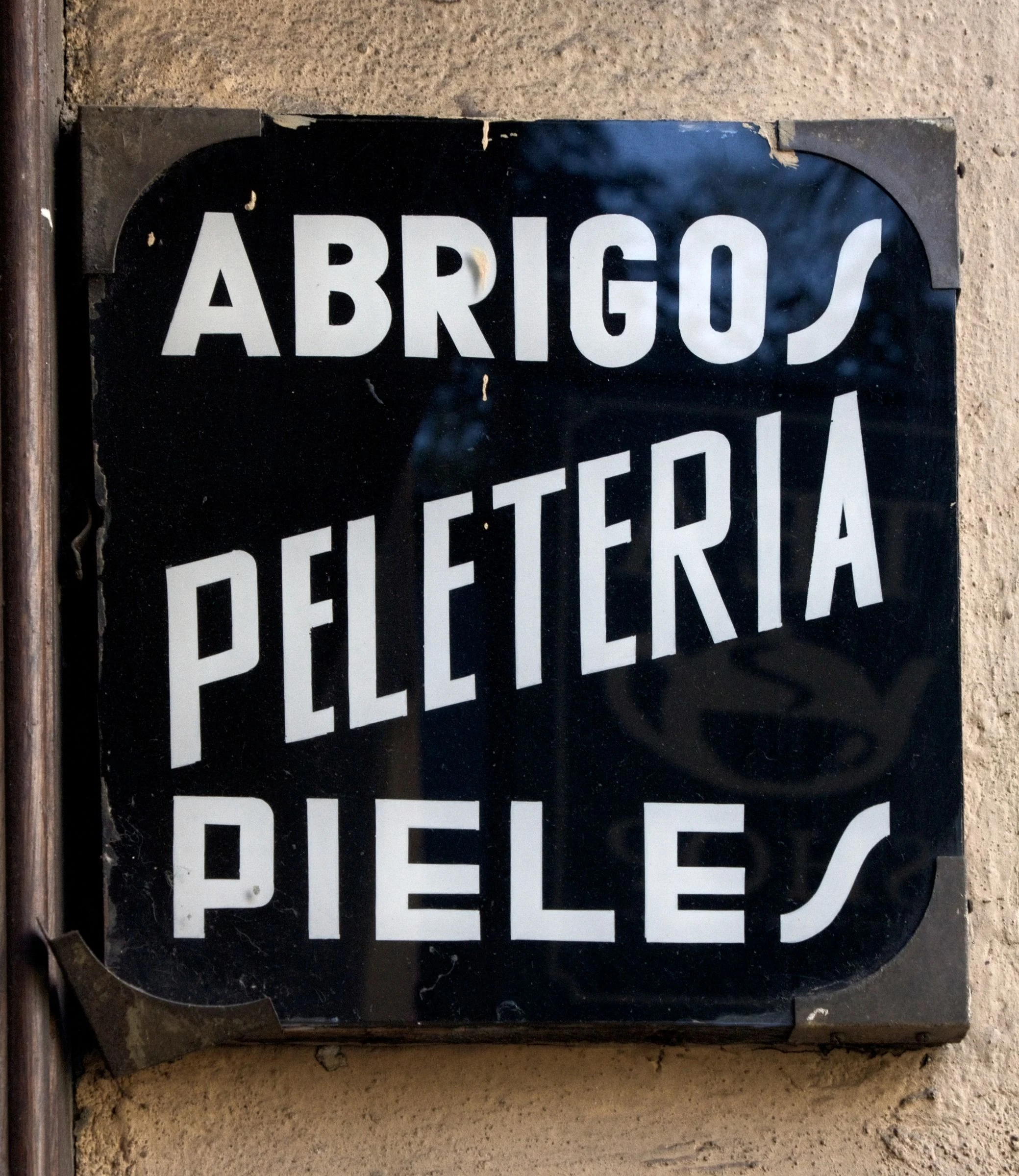 White Spanish lettering on a dark shop sign