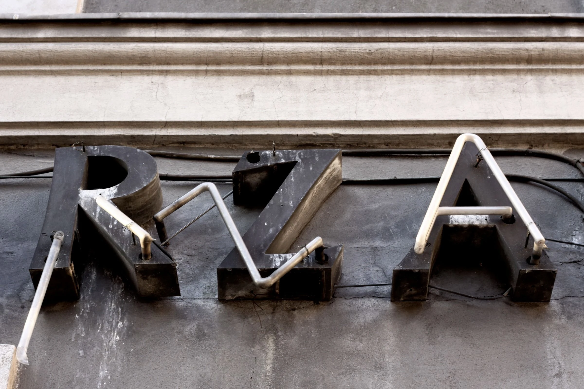 Angular metal letters across a stone facade