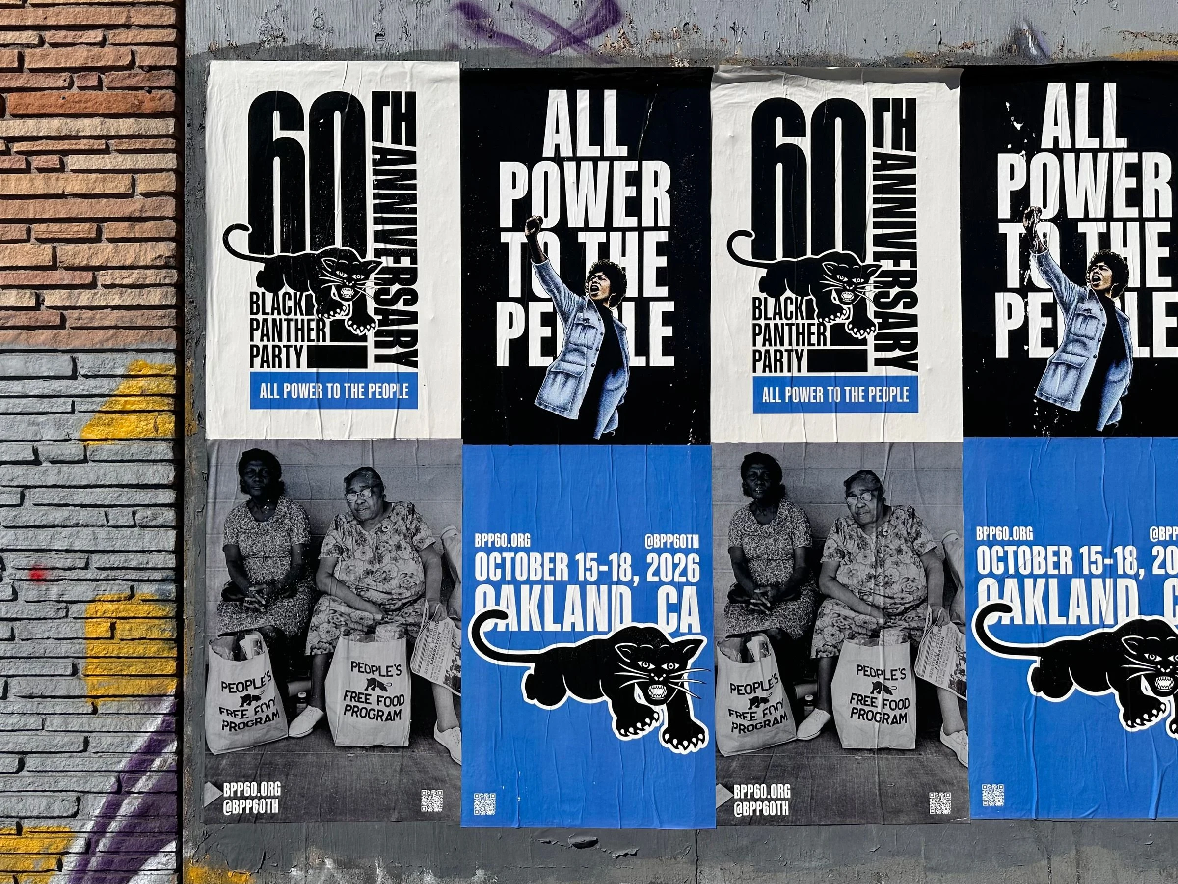 Wheatpasted posters for the Black Panther Party 60th anniversary on a gray wall: ALL POWER TO THE PEOPLE with a raised-fist figure, a black panther, two women holding People's Free Food Program bags, and October 15-18, 2026, Oakland, CA in white on blue